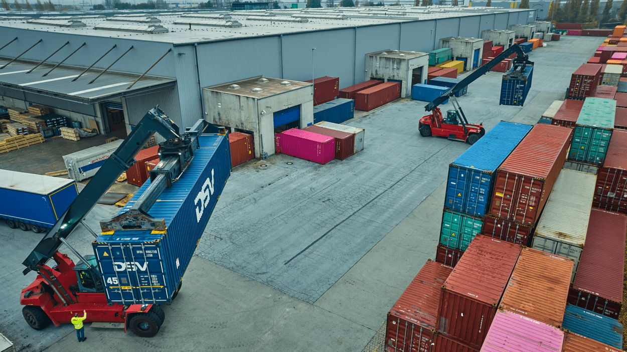 Trucks bærer og distribuerer DSV-containere  utenfor terminal, som blir plassert oppå hverandre